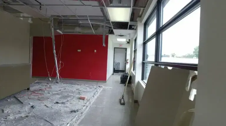 The green room before, mid demolition, a red wall and rubble on the floor