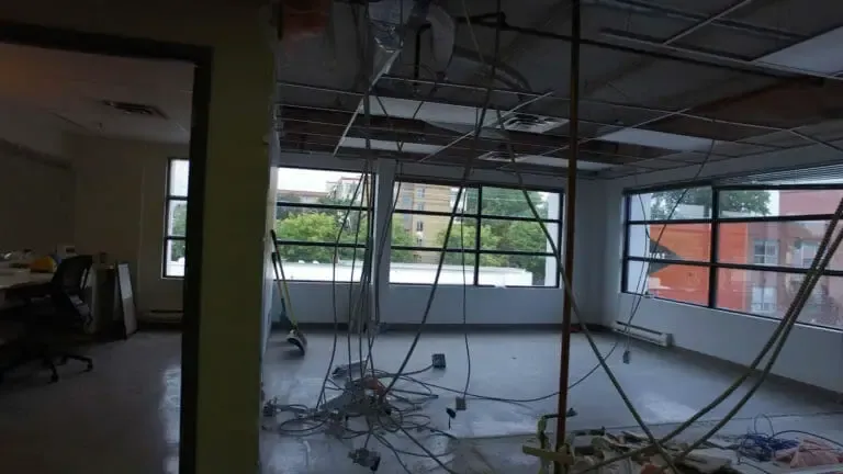The kitchen before, an open ceiling, hanging wires and a torn out floor