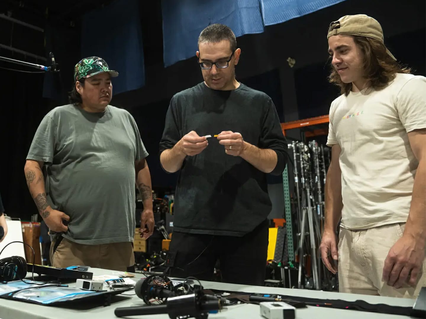Three crew at the camera cart, heads together over a small part