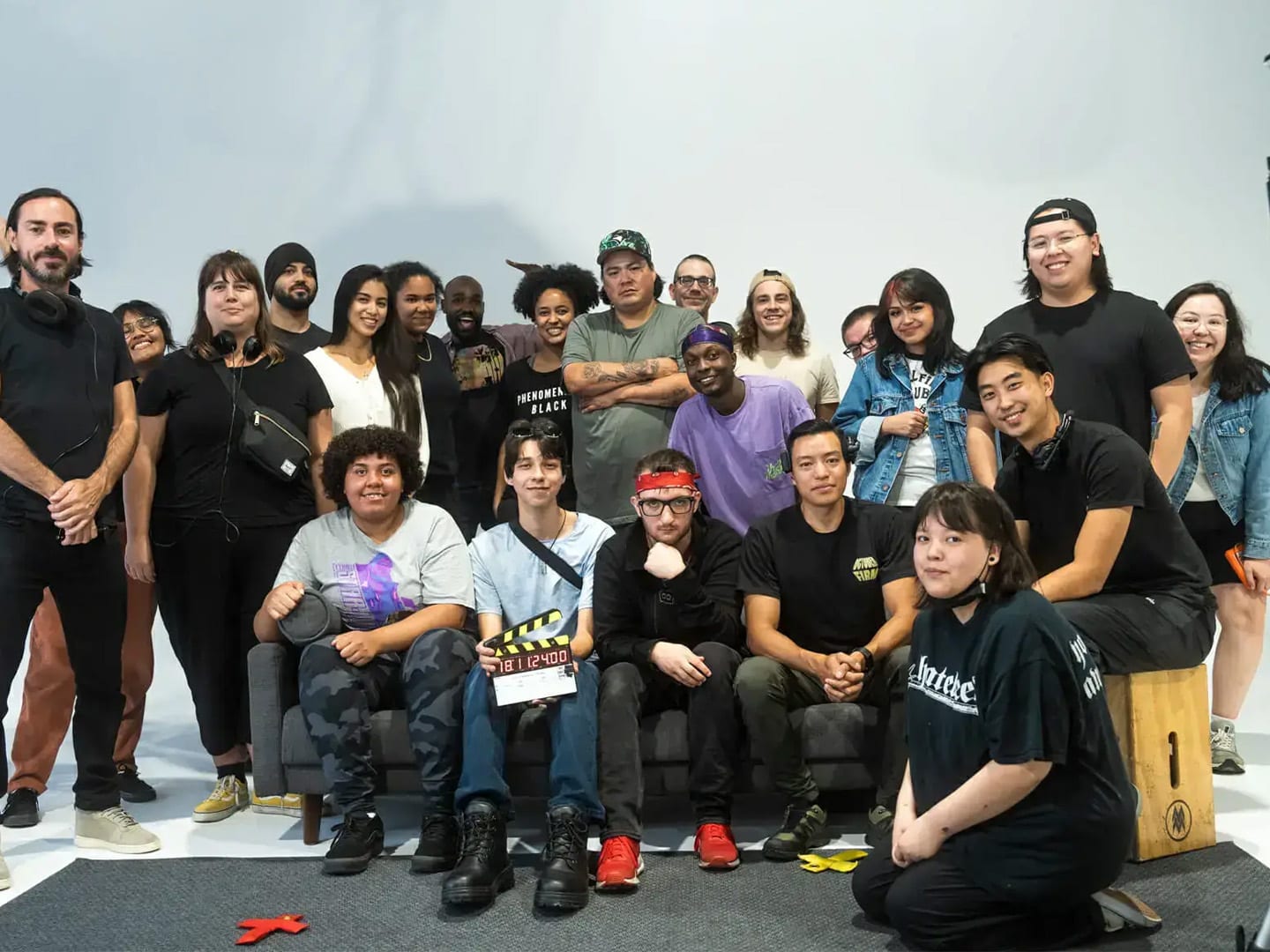 Cast and crew gathered on the cyc for a wrap photo, clapperboard in the front row