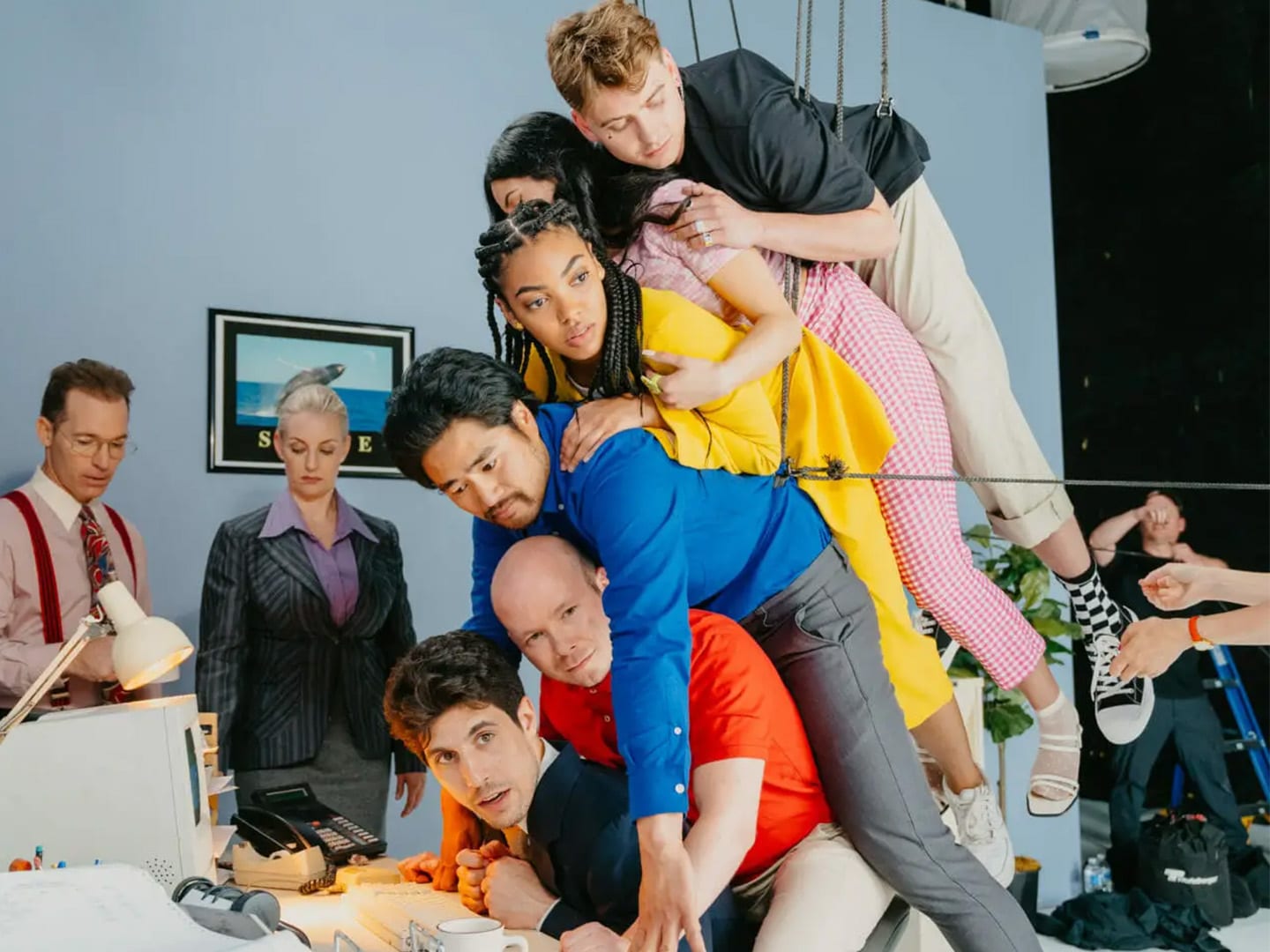 A cast in bright colours piled on top of each other across an apartment set