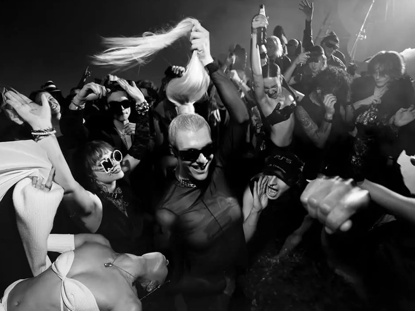 A packed dance floor shot in black and white, arms up in the crowd