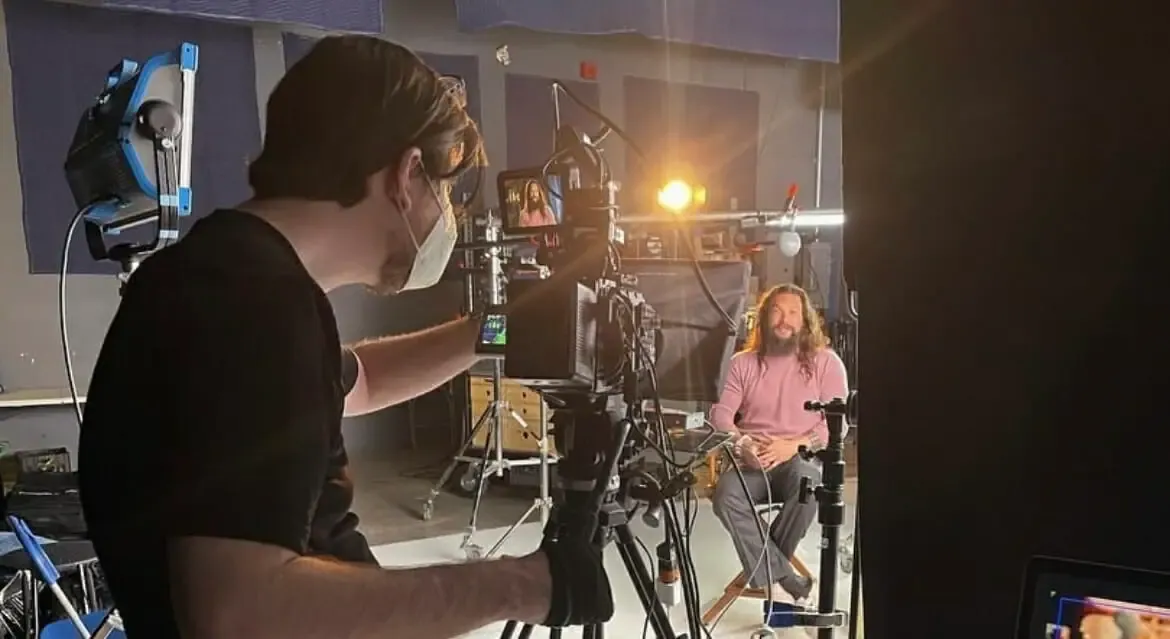 Adam Griffiths behind the camera on an interview shoot in the studio, the seated guest lit across the set