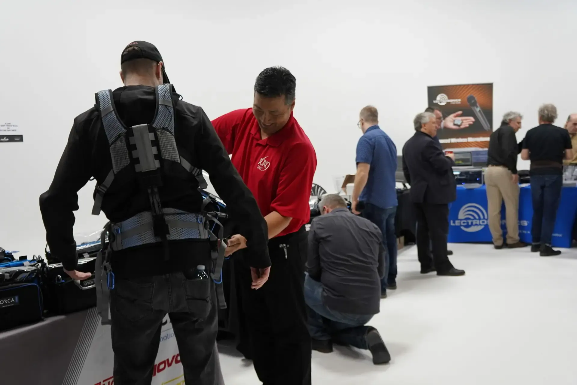 Vendors demonstrating audio gear to visitors at a trade show on the stage