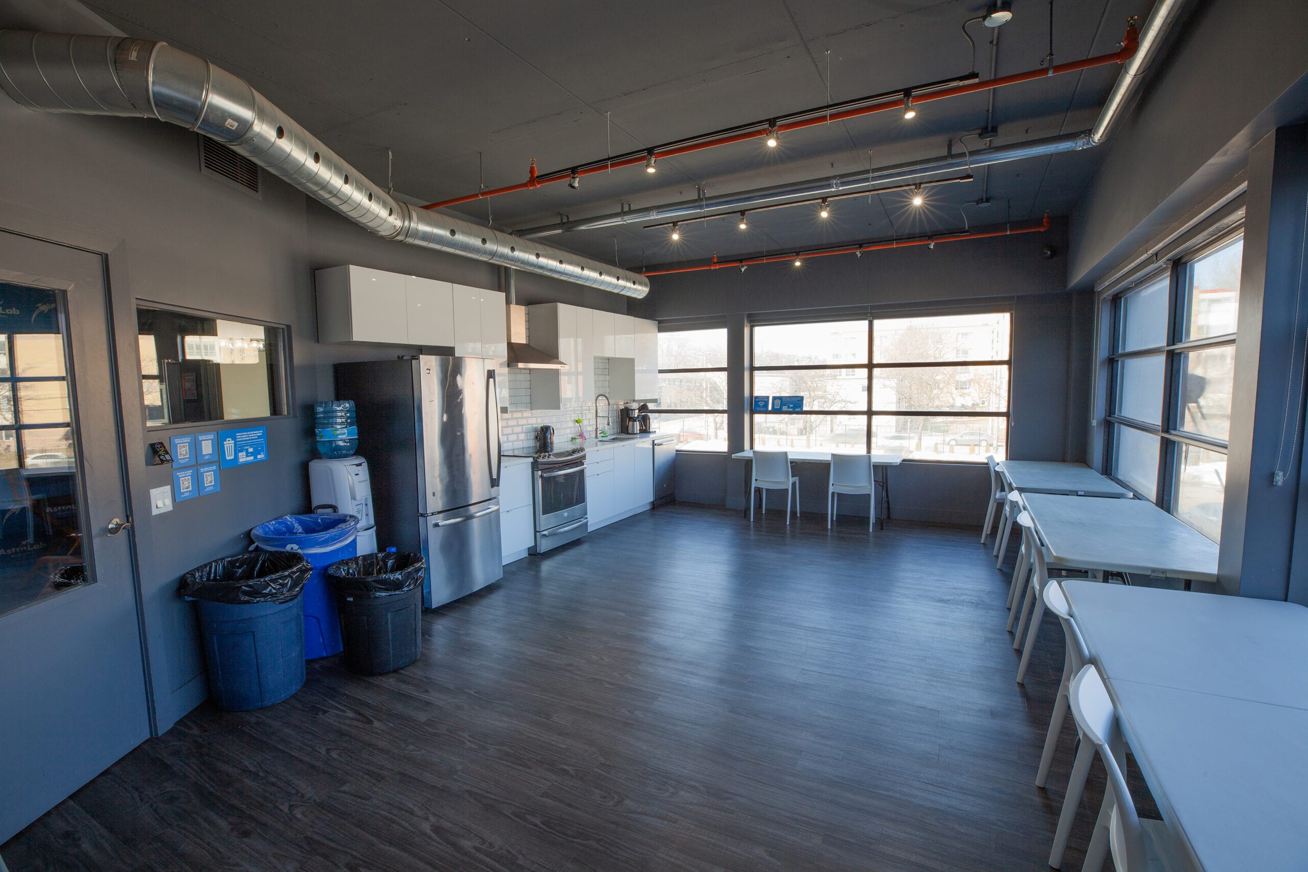 The kitchen and lounge, a full kitchen at the far end and long tables along the windows