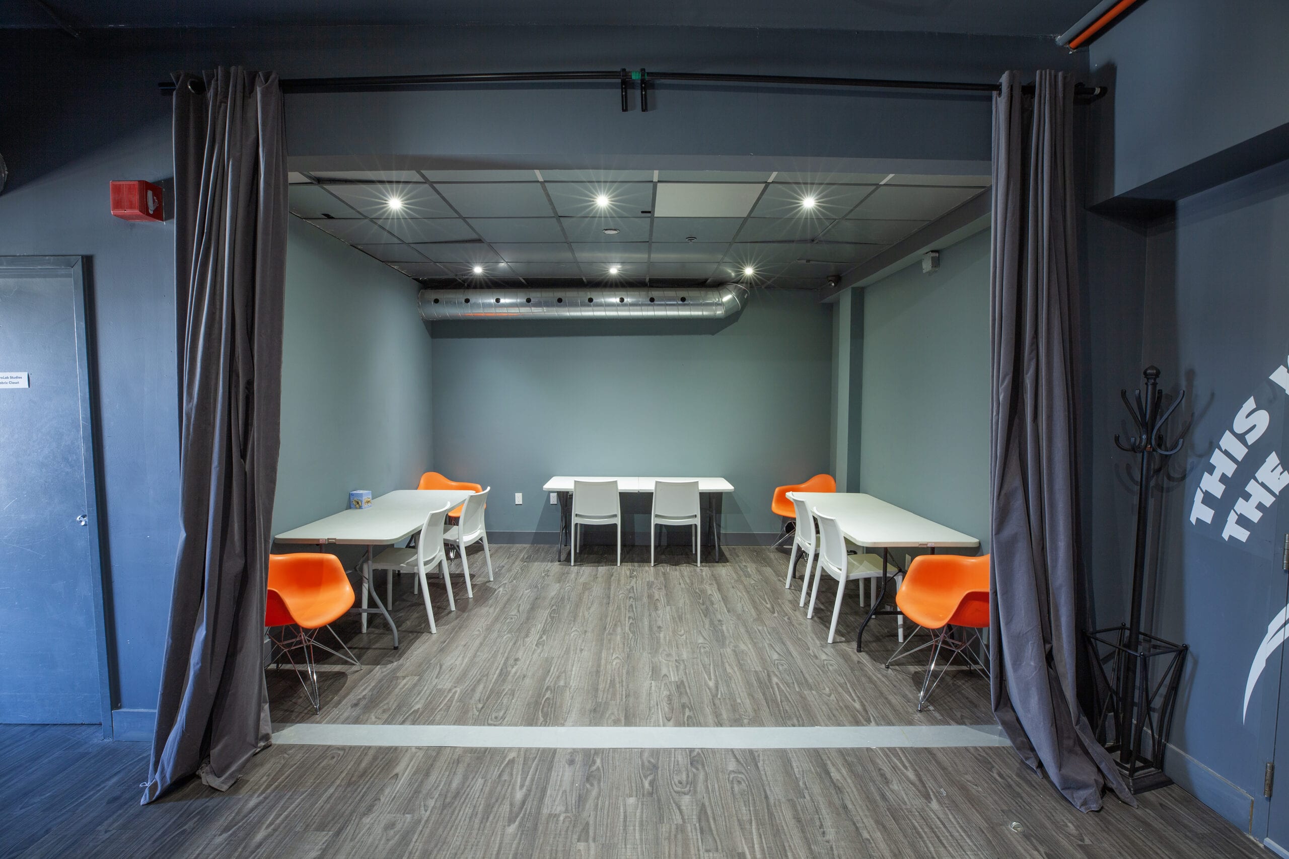 The multi-purpose room with its curtains drawn back, tables and orange chairs set out