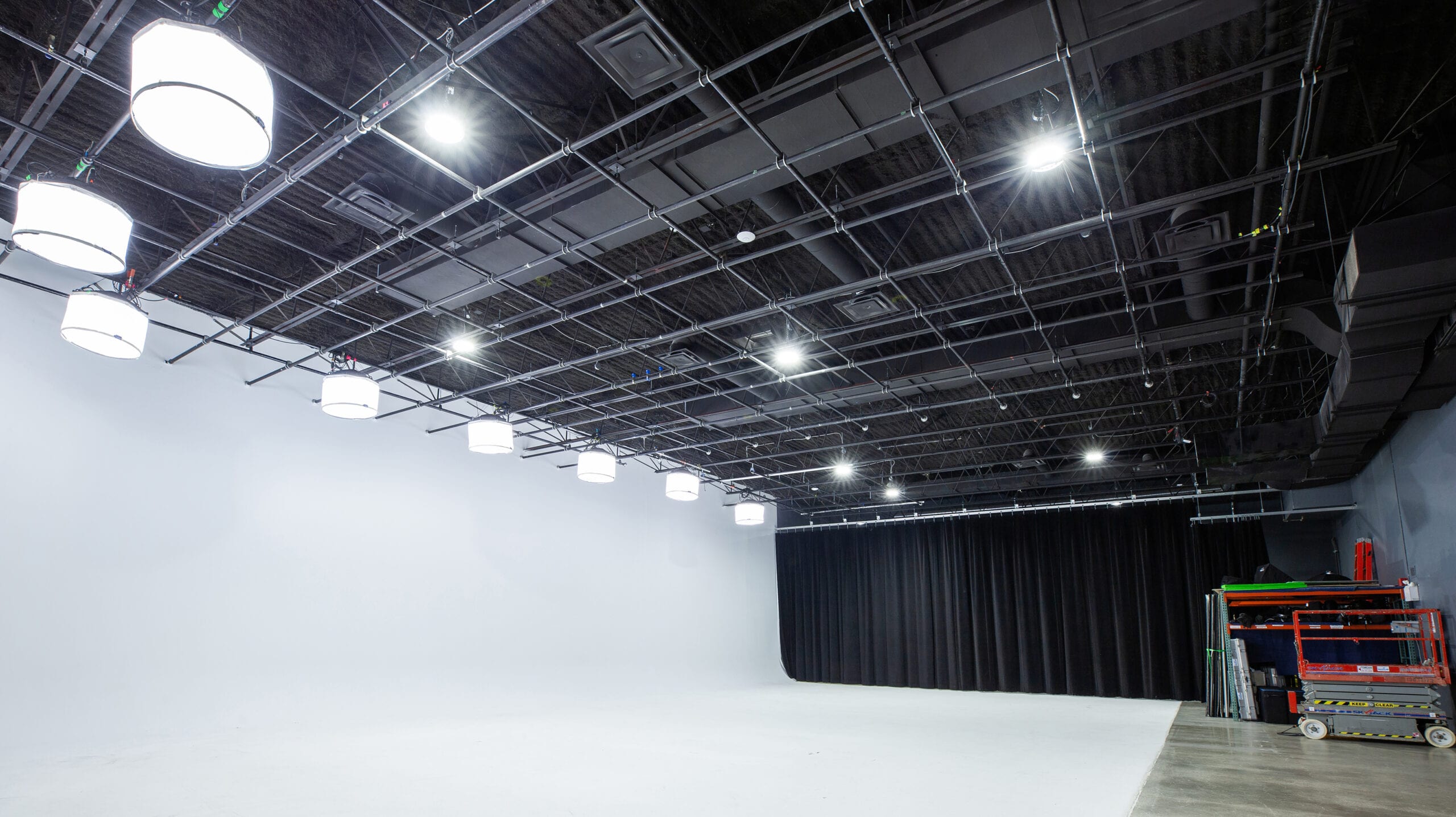 The stage with a black curtain drawn along the far wall, the white cyc to its left and the lighting grid overhead